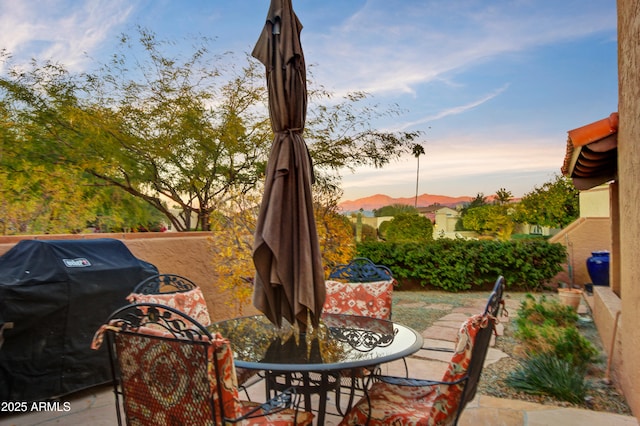 patio terrace at dusk with a mountain view and area for grilling