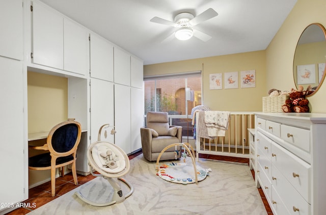 bedroom featuring dark tile patterned flooring, a nursery area, and ceiling fan