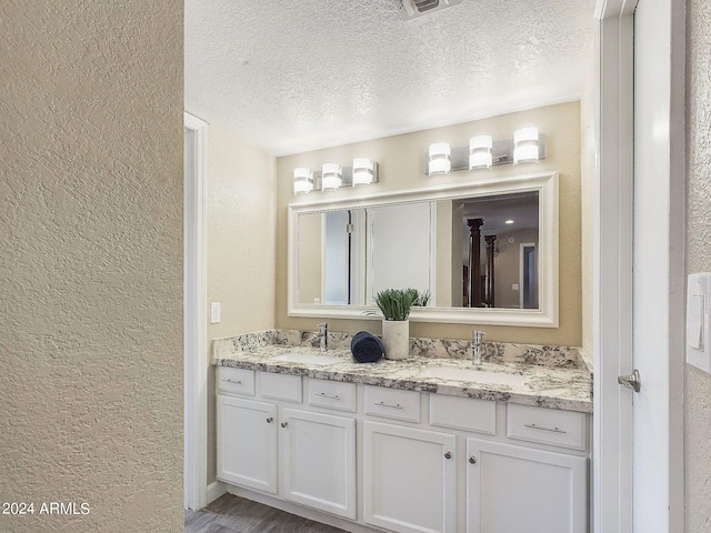 bathroom with vanity, wood-type flooring, and a textured ceiling