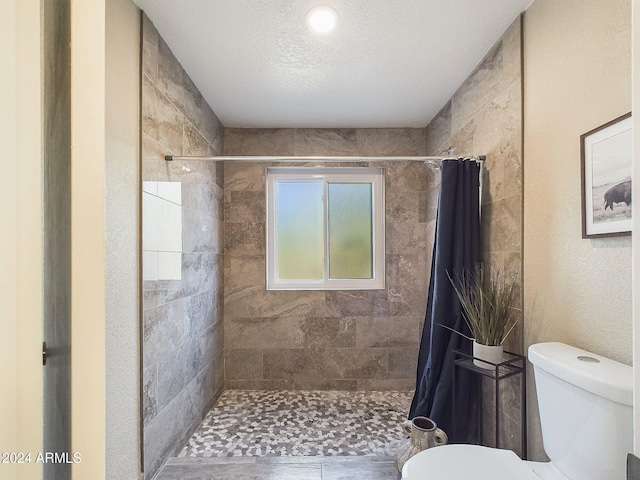 bathroom featuring toilet, a textured ceiling, and a shower with shower curtain