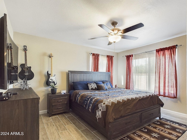 bedroom with a textured ceiling, light hardwood / wood-style flooring, and ceiling fan