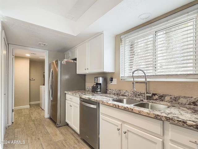 kitchen with light wood-type flooring, stainless steel appliances, white cabinetry, and sink