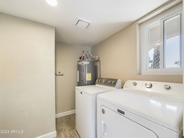 clothes washing area with washing machine and dryer, light hardwood / wood-style flooring, and water heater