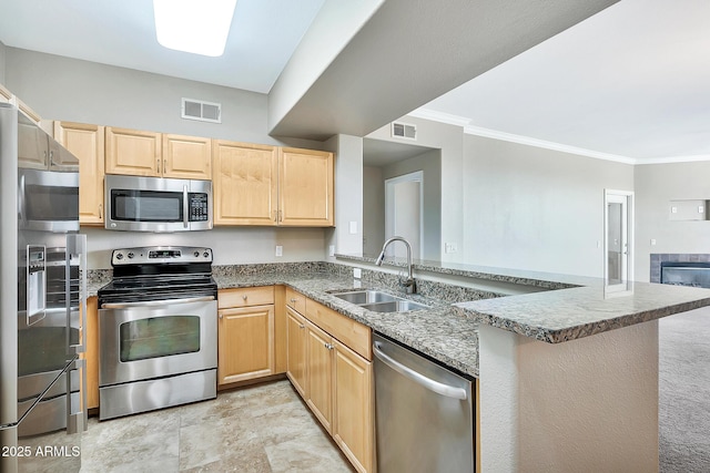 kitchen featuring stainless steel appliances, light brown cabinets, visible vents, and a sink