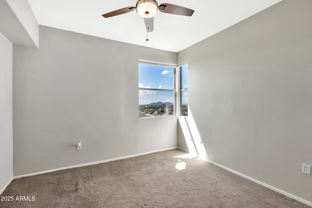 carpeted empty room featuring a ceiling fan and baseboards