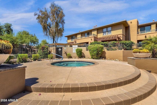 view of swimming pool with a community hot tub and fence