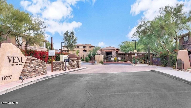 view of street with a residential view, sidewalks, a gated entry, and curbs