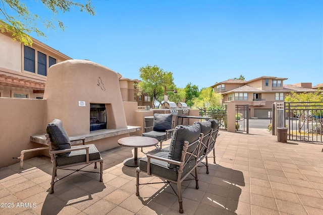 view of patio featuring a residential view, an outdoor fireplace, and fence