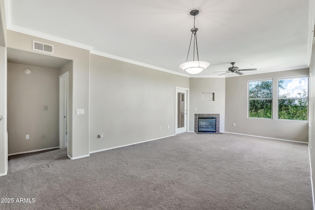 unfurnished living room featuring a tiled fireplace, baseboards, visible vents, a ceiling fan, and ornamental molding