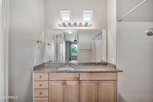 full bath featuring shower / washtub combination, a textured wall, and vanity