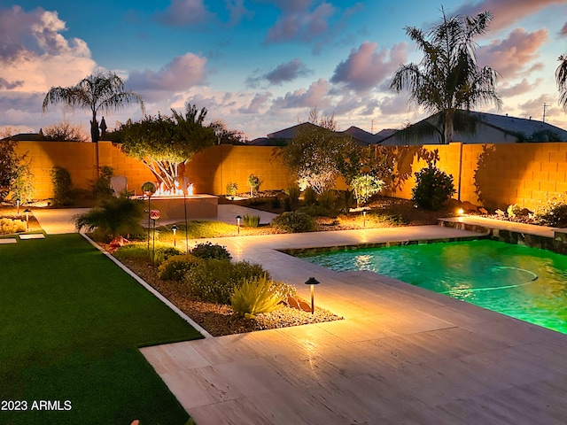 pool at dusk featuring a yard