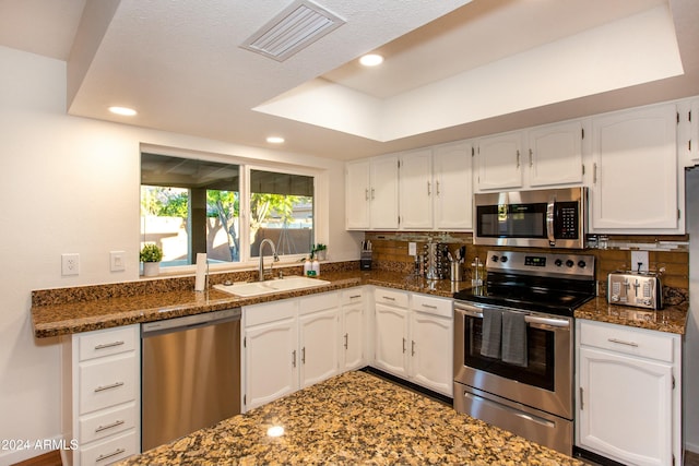 kitchen with visible vents, decorative backsplash, appliances with stainless steel finishes, white cabinets, and a sink