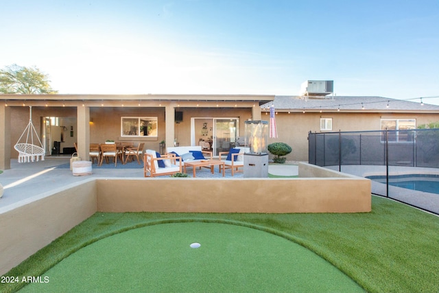 rear view of property with a fenced in pool, stucco siding, outdoor lounge area, central AC unit, and a patio area