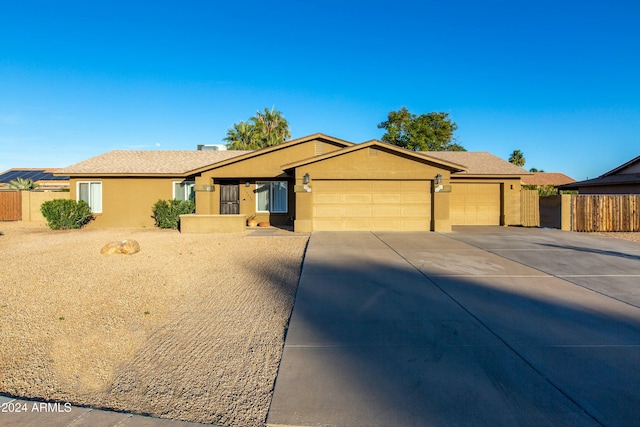 ranch-style house with a garage, fence, and stucco siding