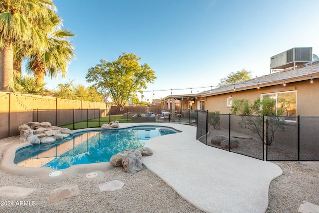 view of pool with a fenced in pool, a fenced backyard, a patio, and central AC unit