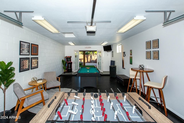 game room featuring a garage, concrete block wall, and pool table