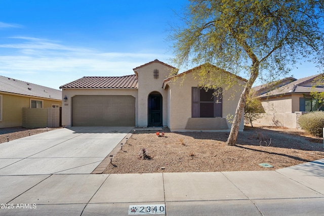 mediterranean / spanish-style house featuring stucco siding, driveway, a tile roof, fence, and an attached garage