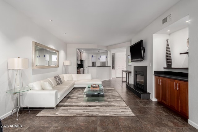 living room with a glass covered fireplace, visible vents, and baseboards