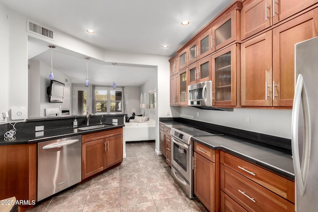 kitchen with brown cabinets, dark countertops, visible vents, appliances with stainless steel finishes, and a sink