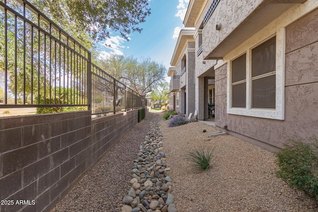 view of side of property with fence and stucco siding