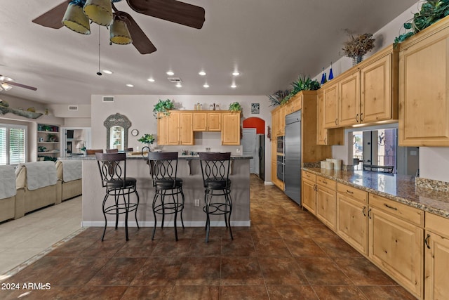 kitchen with light brown cabinetry, a kitchen breakfast bar, appliances with stainless steel finishes, and ceiling fan