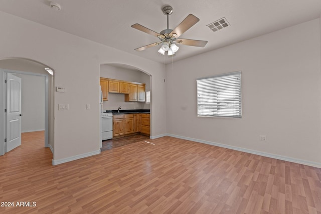 unfurnished living room with light hardwood / wood-style floors, sink, and ceiling fan