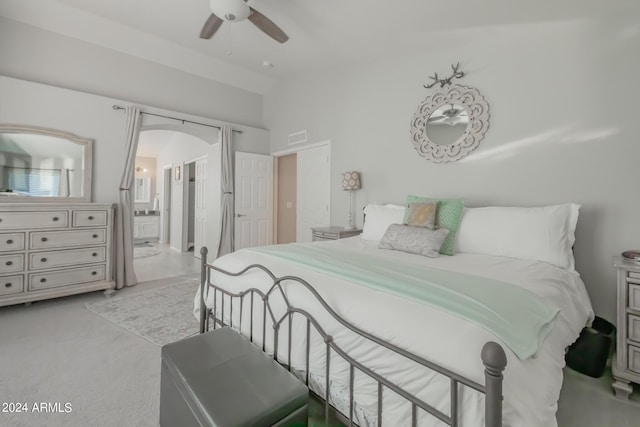 carpeted bedroom with vaulted ceiling, connected bathroom, and ceiling fan