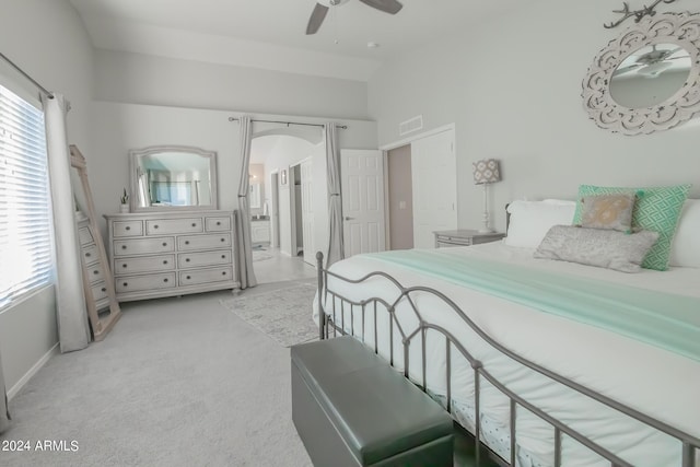 carpeted bedroom featuring connected bathroom, multiple windows, and ceiling fan