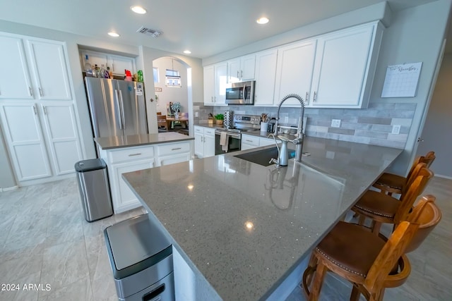 kitchen featuring sink, stainless steel appliances, a breakfast bar area, and white cabinetry