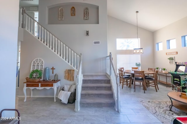 staircase with high vaulted ceiling and tile patterned floors