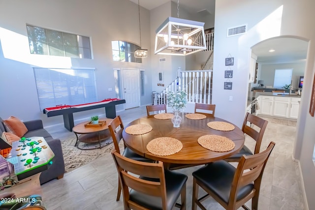 tiled dining space with a high ceiling and an inviting chandelier