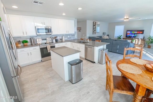 kitchen featuring sink, white cabinets, kitchen peninsula, a kitchen island, and appliances with stainless steel finishes