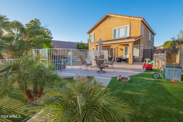 back of house with a patio and a lawn