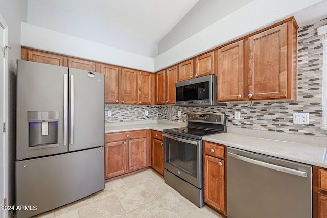 kitchen with appliances with stainless steel finishes, light tile patterned floors, vaulted ceiling, and backsplash