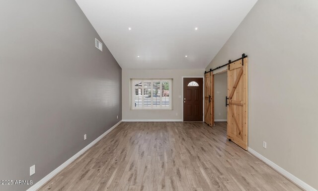 6457 E Encanto St, Mesa, AZ 85205 - interior space with a barn door, light wood-type flooring, visible vents, vaulted ceiling, and baseboards