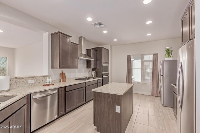 2881 N Riverside Dr, Florence, AZ 85132 - kitchen featuring appliances with stainless steel finishes, wall chimney exhaust hood, dark brown cabinetry, a center island, and recessed lighting