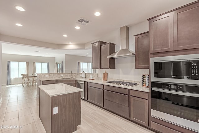 2881 N Riverside Dr, Florence, AZ 85132 - kitchen featuring appliances with stainless steel finishes, wall chimney range hood, a sink, light stone countertops, and a peninsula
