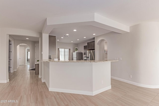 2881 N Riverside Dr, Florence, AZ 85132 - kitchen featuring stainless steel refrigerator with ice dispenser, arched walkways, freestanding refrigerator, light stone countertops, and recessed lighting