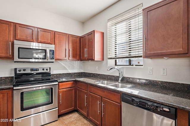 kitchen with dark stone countertops, sink, light tile patterned flooring, and appliances with stainless steel finishes