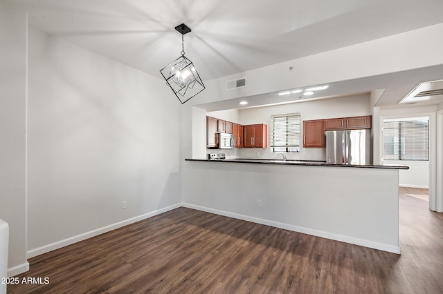 kitchen featuring a healthy amount of sunlight, hanging light fixtures, a notable chandelier, kitchen peninsula, and appliances with stainless steel finishes