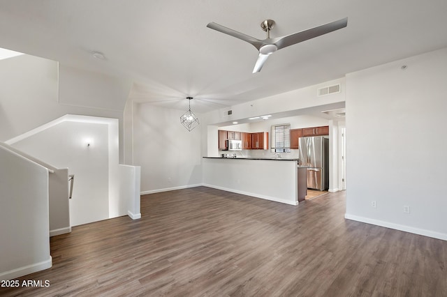 unfurnished living room with dark hardwood / wood-style flooring and ceiling fan with notable chandelier