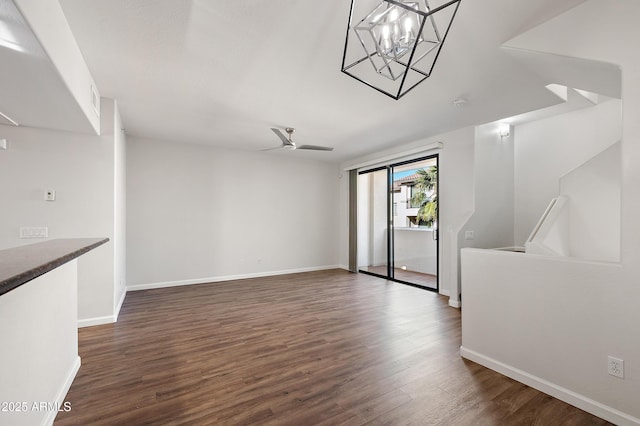 unfurnished living room with ceiling fan with notable chandelier and dark hardwood / wood-style floors