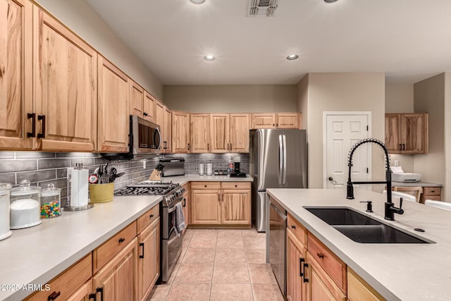 kitchen featuring stainless steel appliances, a sink, visible vents, light countertops, and tasteful backsplash