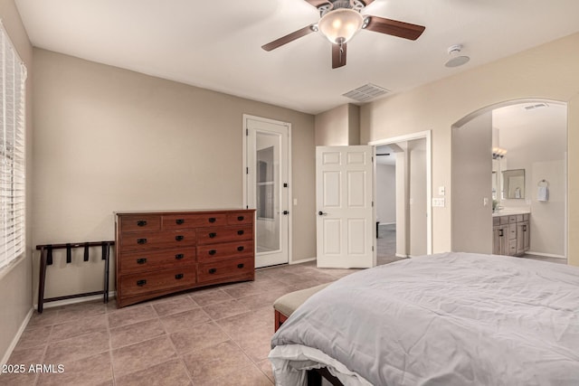 bedroom with arched walkways, visible vents, ensuite bathroom, light tile patterned flooring, and baseboards