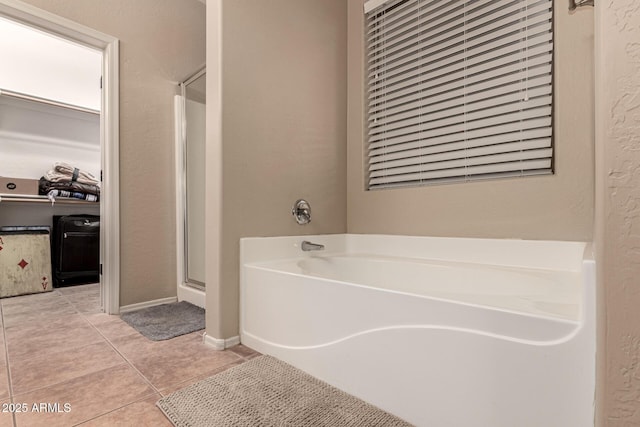 full bath with a walk in closet, tile patterned flooring, a bath, and a shower stall