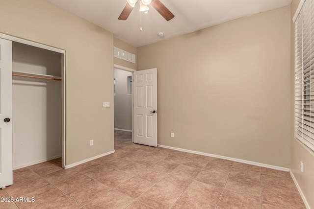 unfurnished bedroom with light tile patterned floors, a closet, a ceiling fan, and baseboards