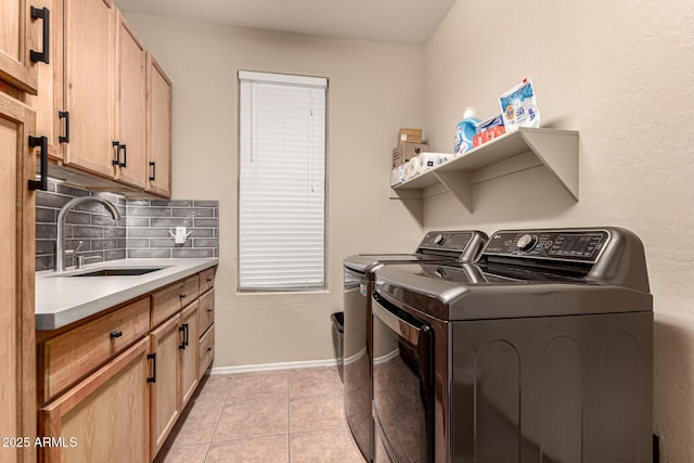 laundry area with light tile patterned floors, cabinet space, a sink, separate washer and dryer, and baseboards