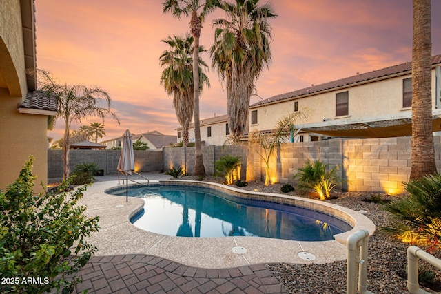 pool at dusk featuring a patio, a fenced backyard, and a fenced in pool