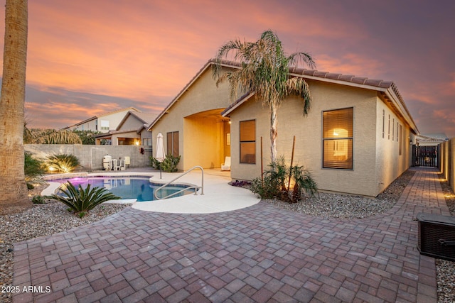 back of house featuring stucco siding, a fenced backyard, a fenced in pool, and a patio