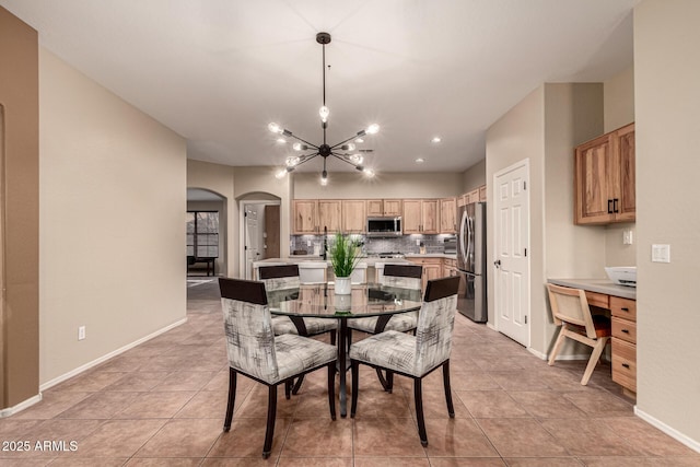 dining area featuring arched walkways, a notable chandelier, baseboards, and light tile patterned floors